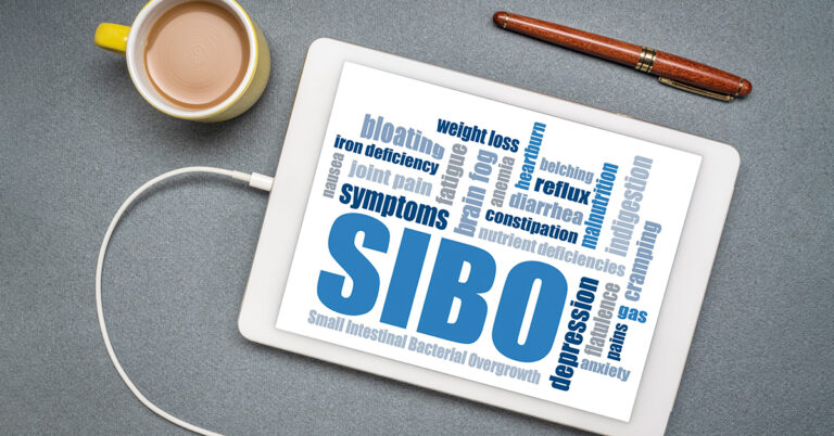A tablet sitting on a table top shows a graphic with words on the screen; the largest word is "SIBO"